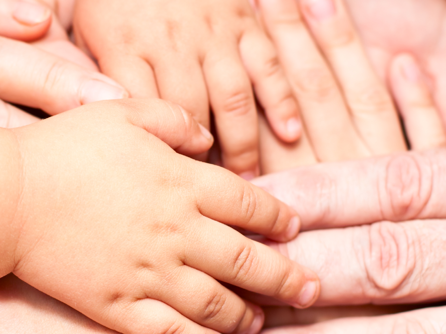 Kinder, junge und alte Menschen haben ihre Hände zusammengelegt. Man sieht die Hände in Großaufnahme.