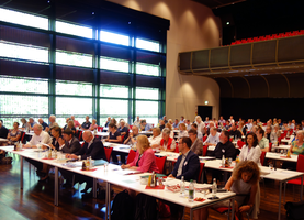 Vertreterinnen und Vertreter der Mitgliedsorganisationen sitzen an Tischen im Bürgerhaus Unterföhring